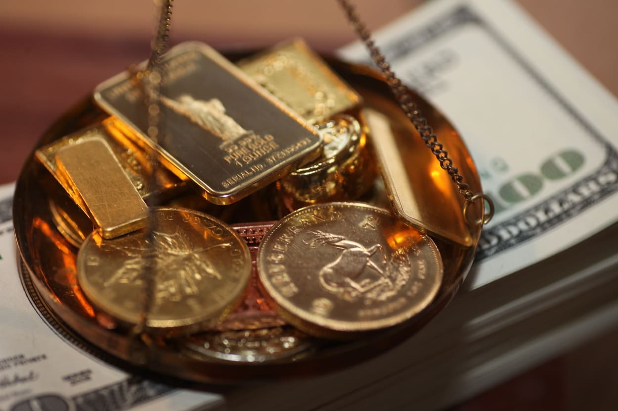Goldbarren und Goldmünzen auf US-Dollar als Symbol für die Risiken einer Goldanlage